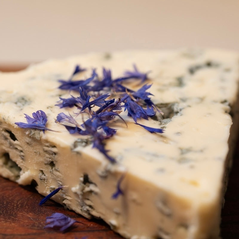 Blue edible cornflower petals on a slice of blue cheese.