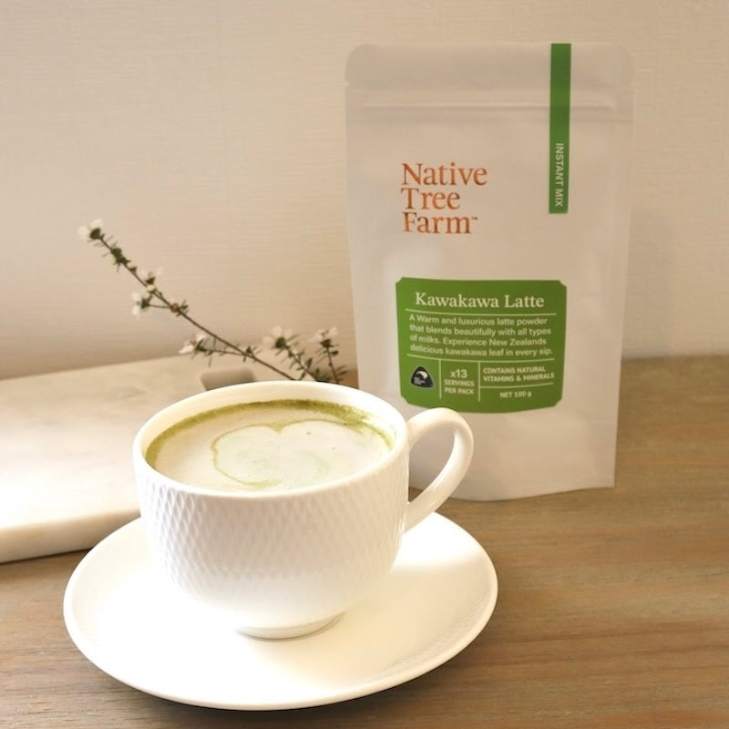 a cup of brewed Native Tree Farm kawakawa latte in a cup on a wooden surface.