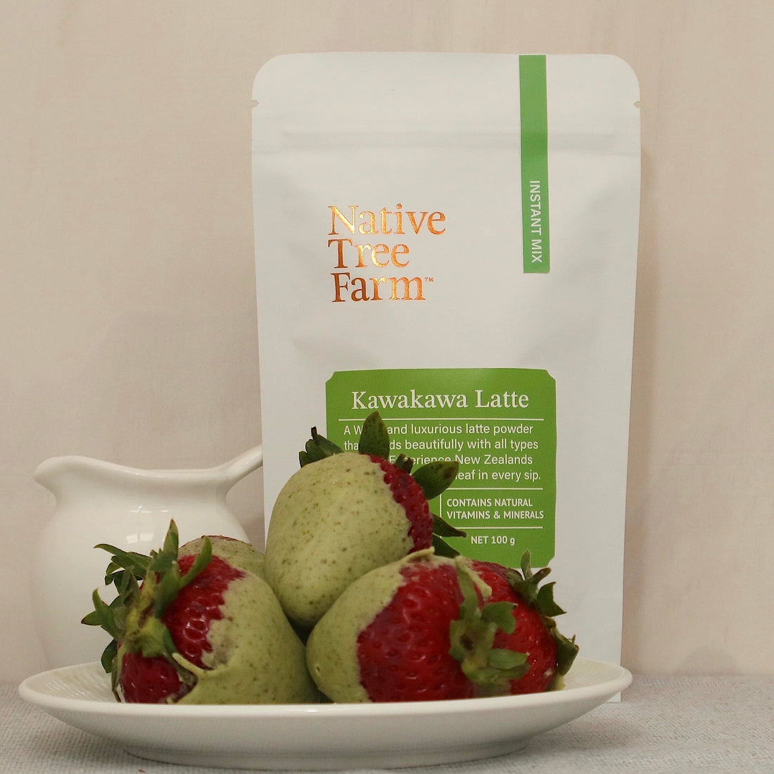 kawakawa latte in background with strawberries coated with kawakawa chocolate on a dish at the front.