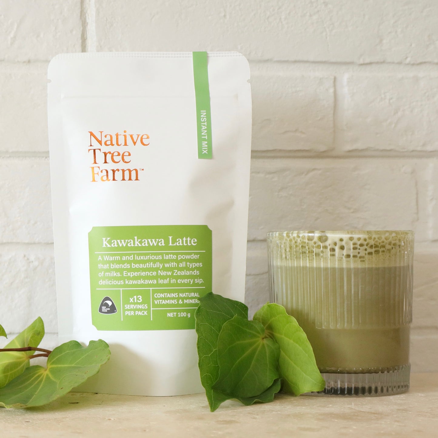 Native Tree Farm Kawakawa Latte package with a glass of latte and leaves on a wooden surface.