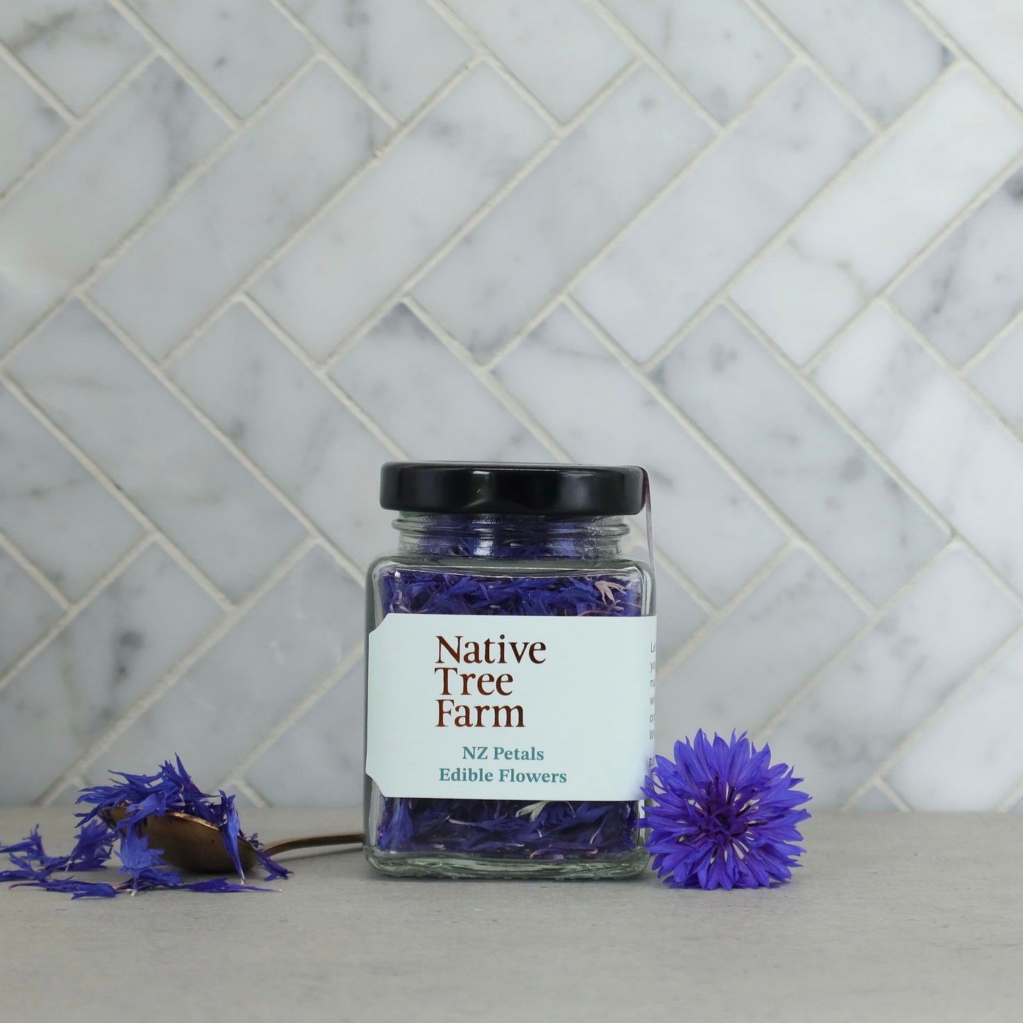 Jar of Native Tree Farm NZ blue Edible petals on a marble kitchen bench