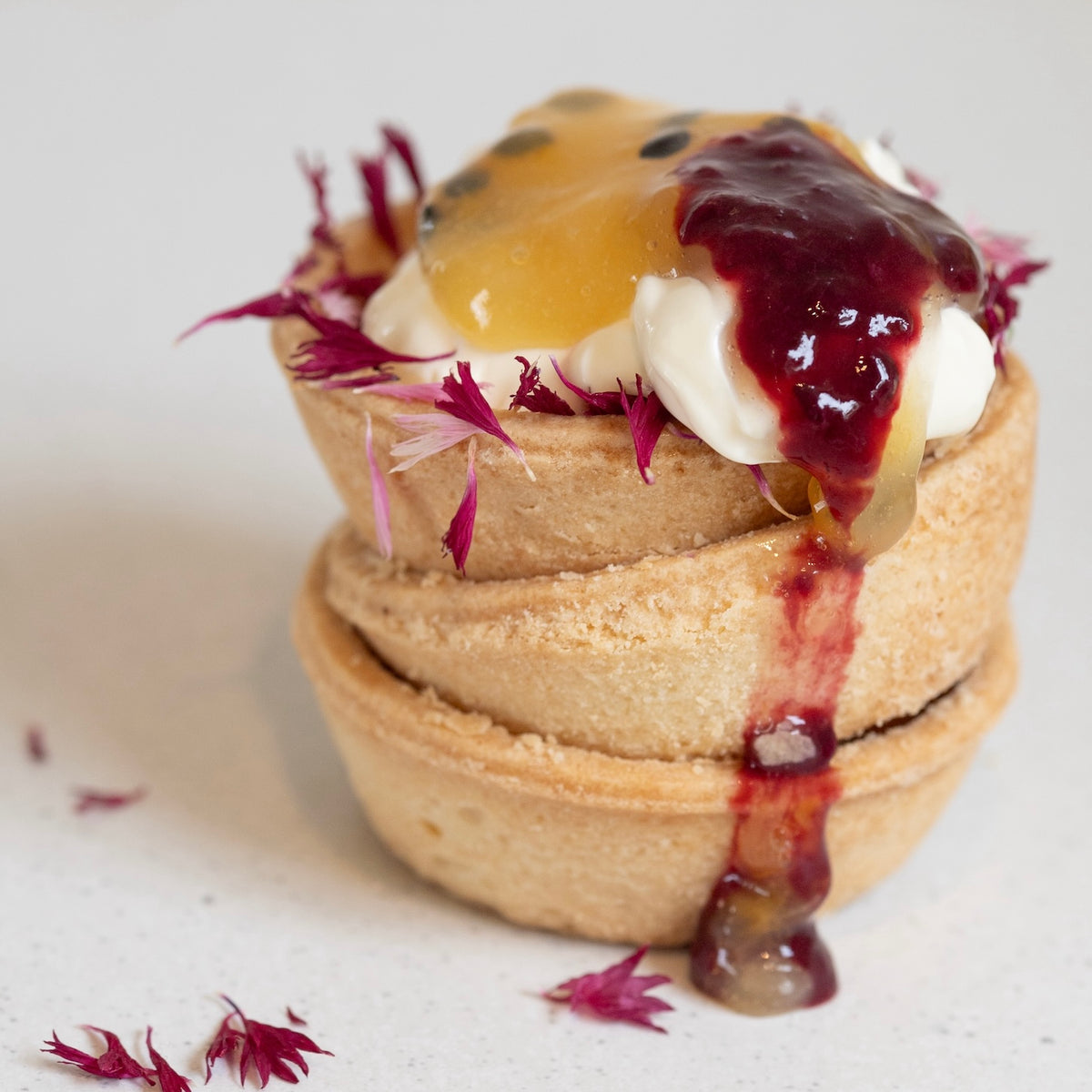 pink cornflower petals from Native Tree Farm on a cream tart.