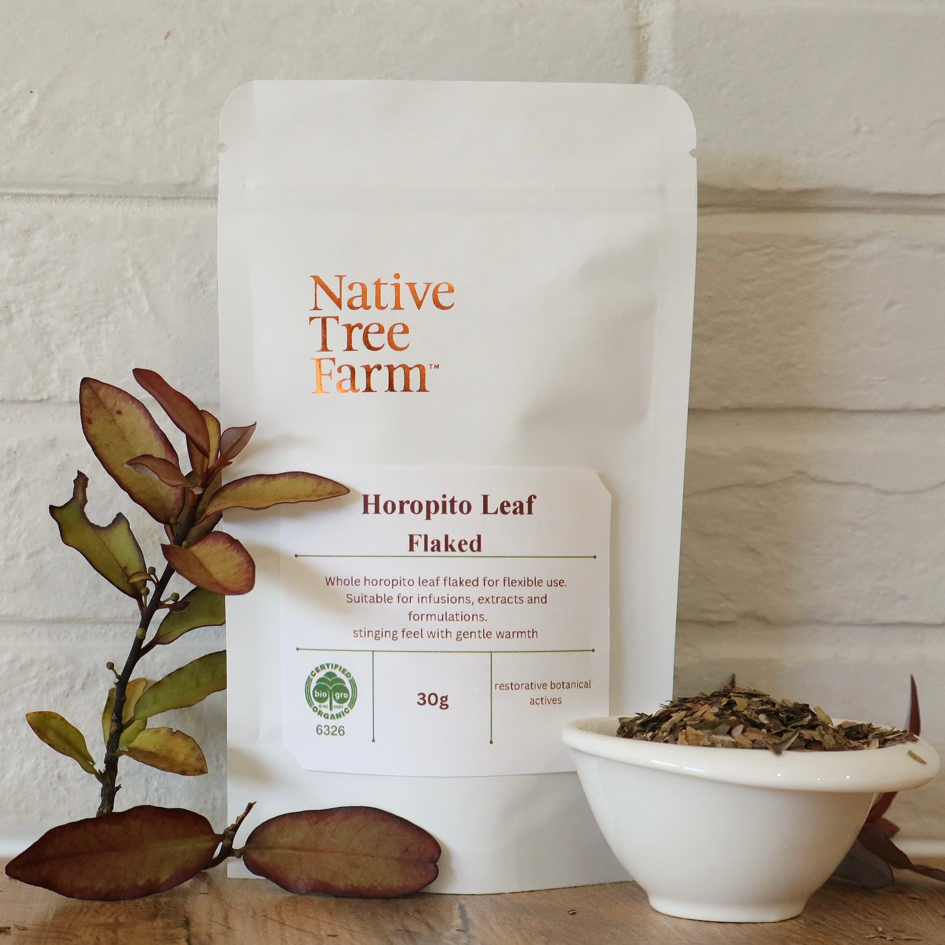 Native Tree Farm Horopito Leaf Flaked packaging with a bowl of horopito leaf on a wooden bench