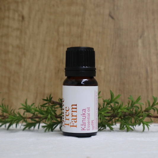 Bottle of Kānuka essential oil from Native tree Farm with green leaves on a wooden background