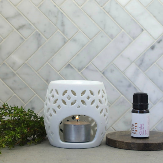 A bottle of native tree farm kanuka essential oil on a stone bench.