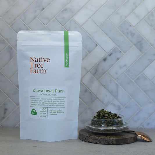 Native Tree Farm Kawakawa herbal tea on a marble and stone bench with a small dish of kawakawa tea leaves.