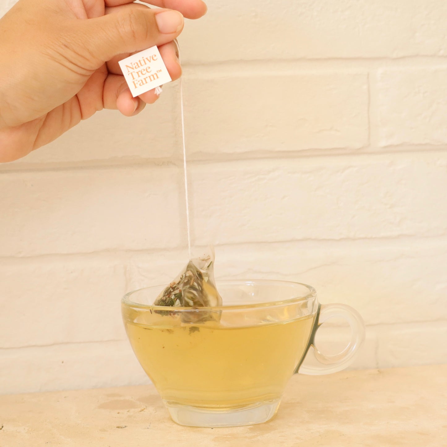 kumaahou Tea bag being added to a glass of tea 
