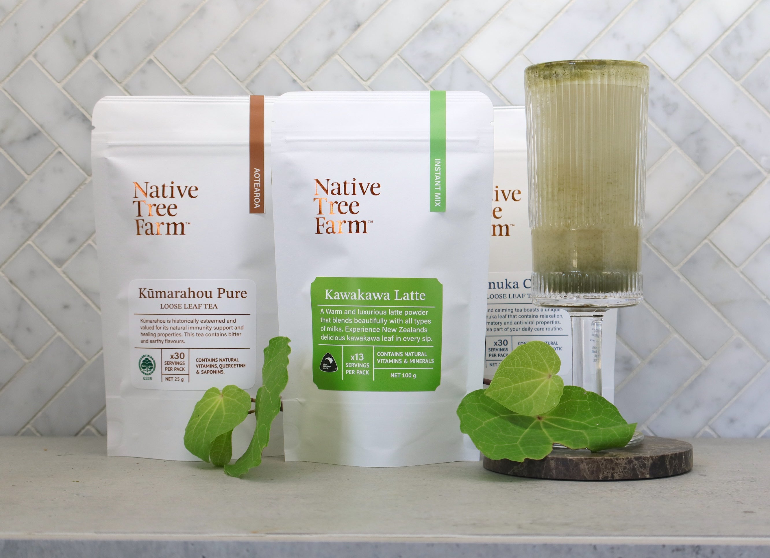 Three packages of Native Tree Farm products on a kitchen bench with a kawakawa latte drink.