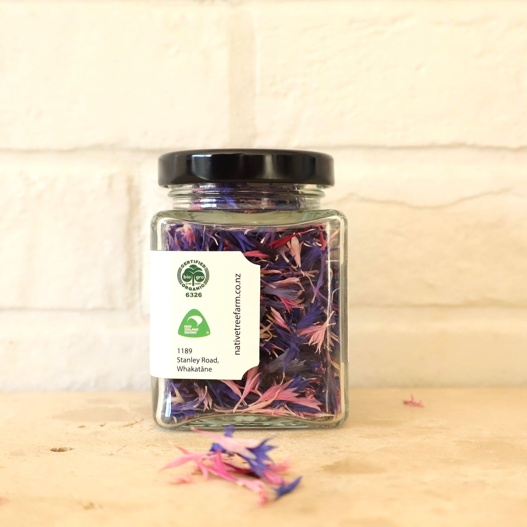 Jar of dried native tree farm edible flowers on a wooden surface
