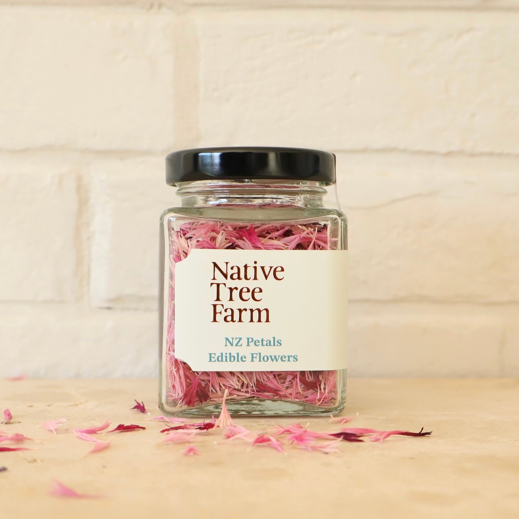 Jar of pink petals from Native Tree Farm on a wooden surface.