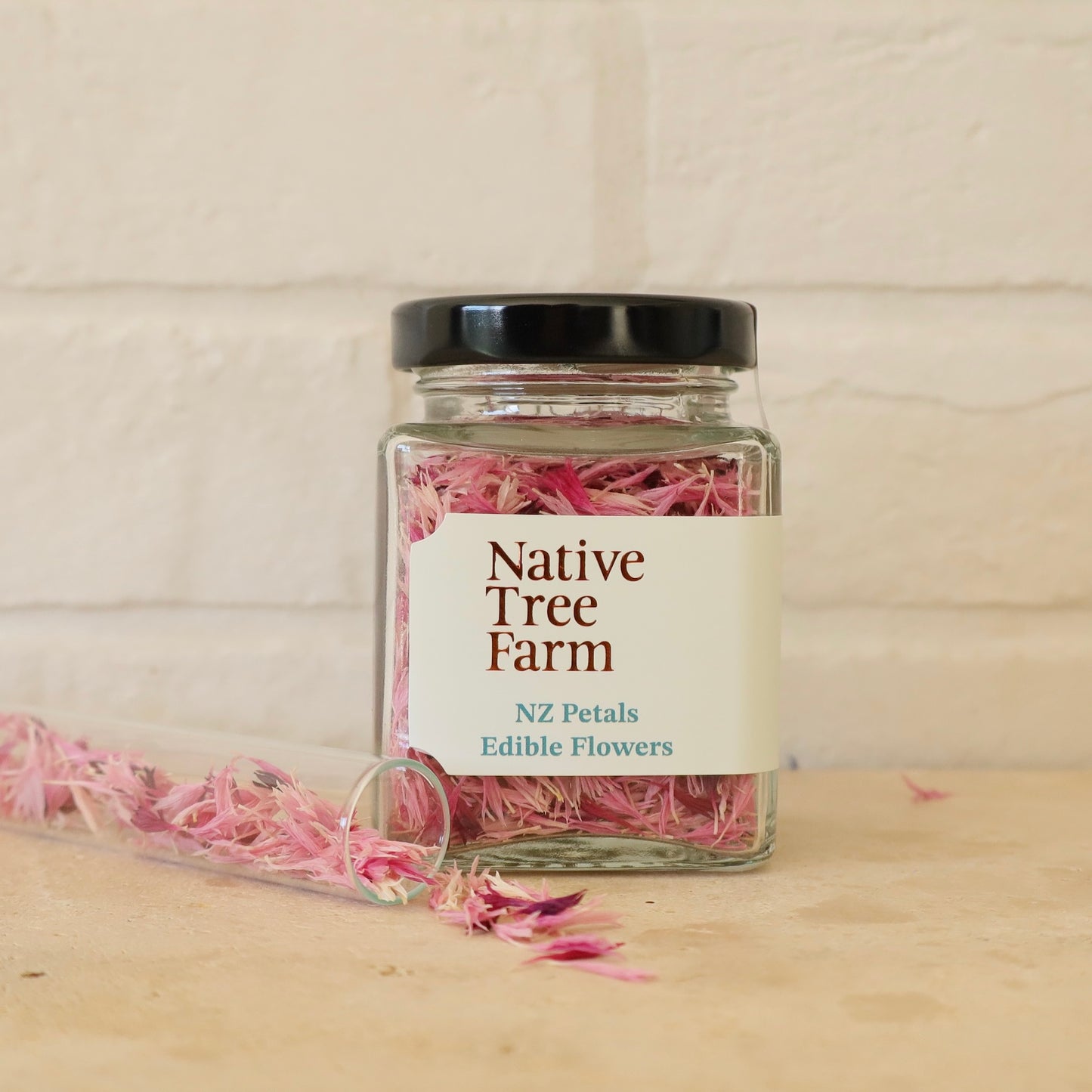 Jar of pink edible flowers from Native Tree Farm on bench