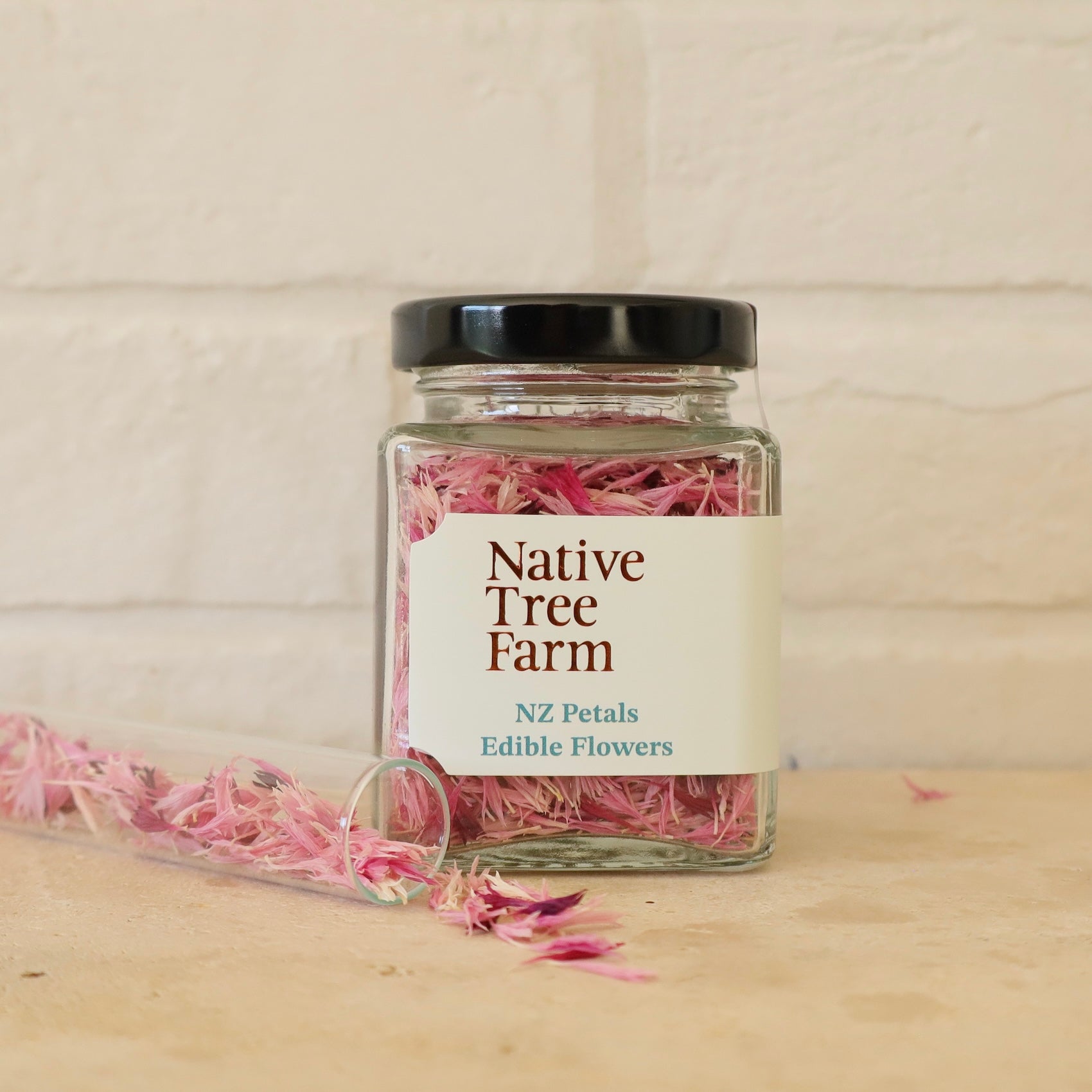 Jar of pink edible flowers from Native Tree Farm on bench