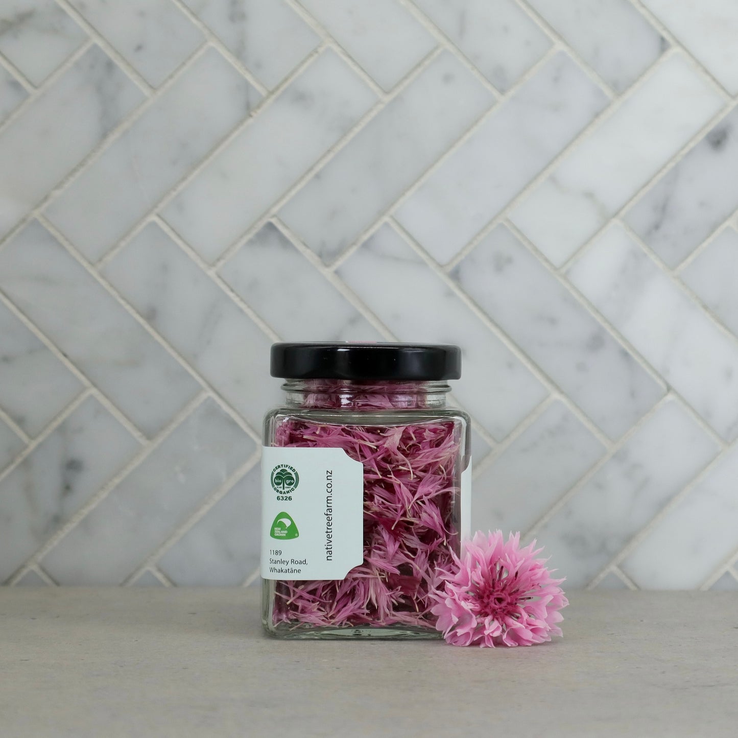side profile of a Jar of Native Tree Farm pink edible flowers on the kitchen table top